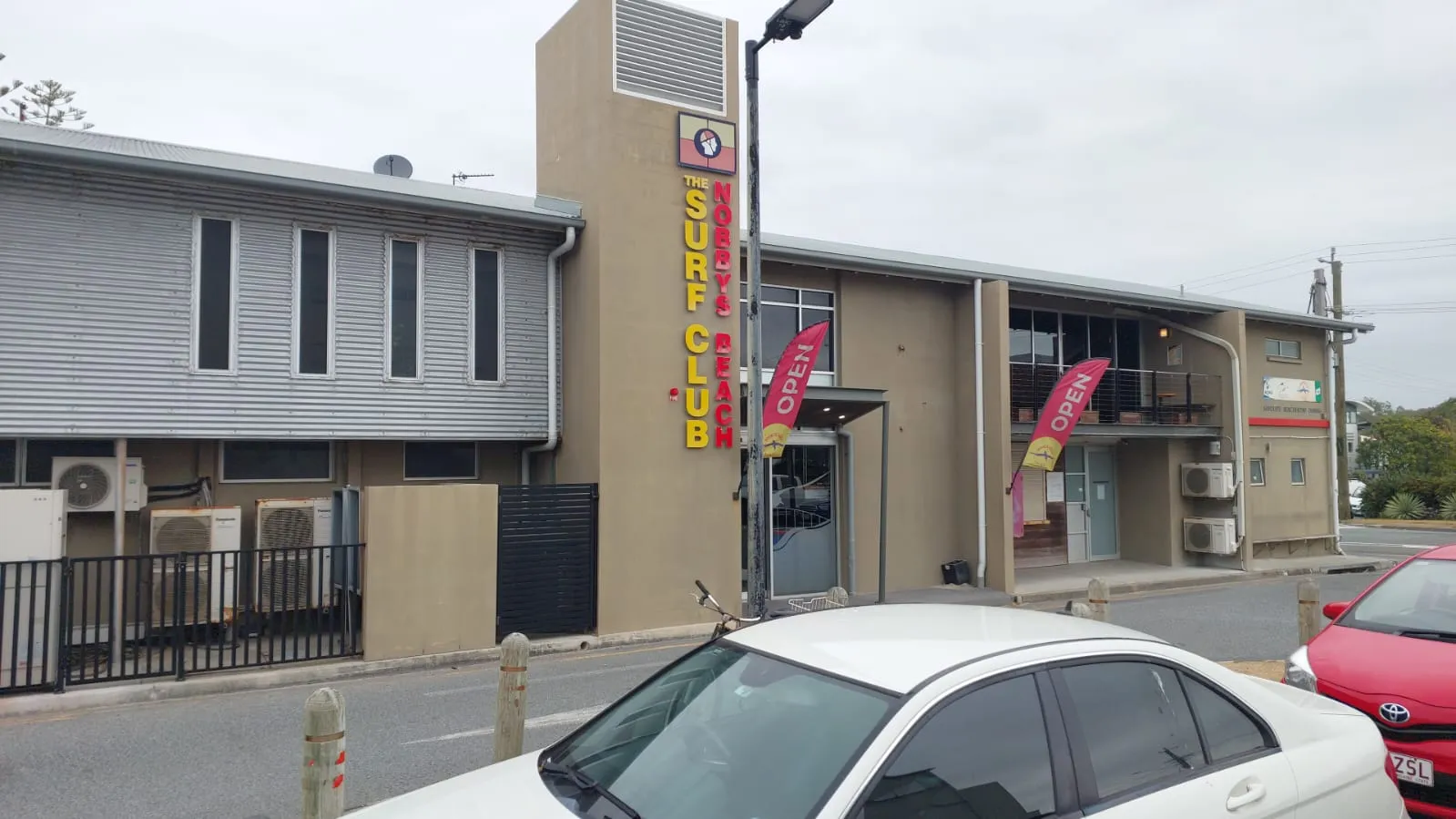 Two-storey Nobbys Beach Surf Club building with open flags out front