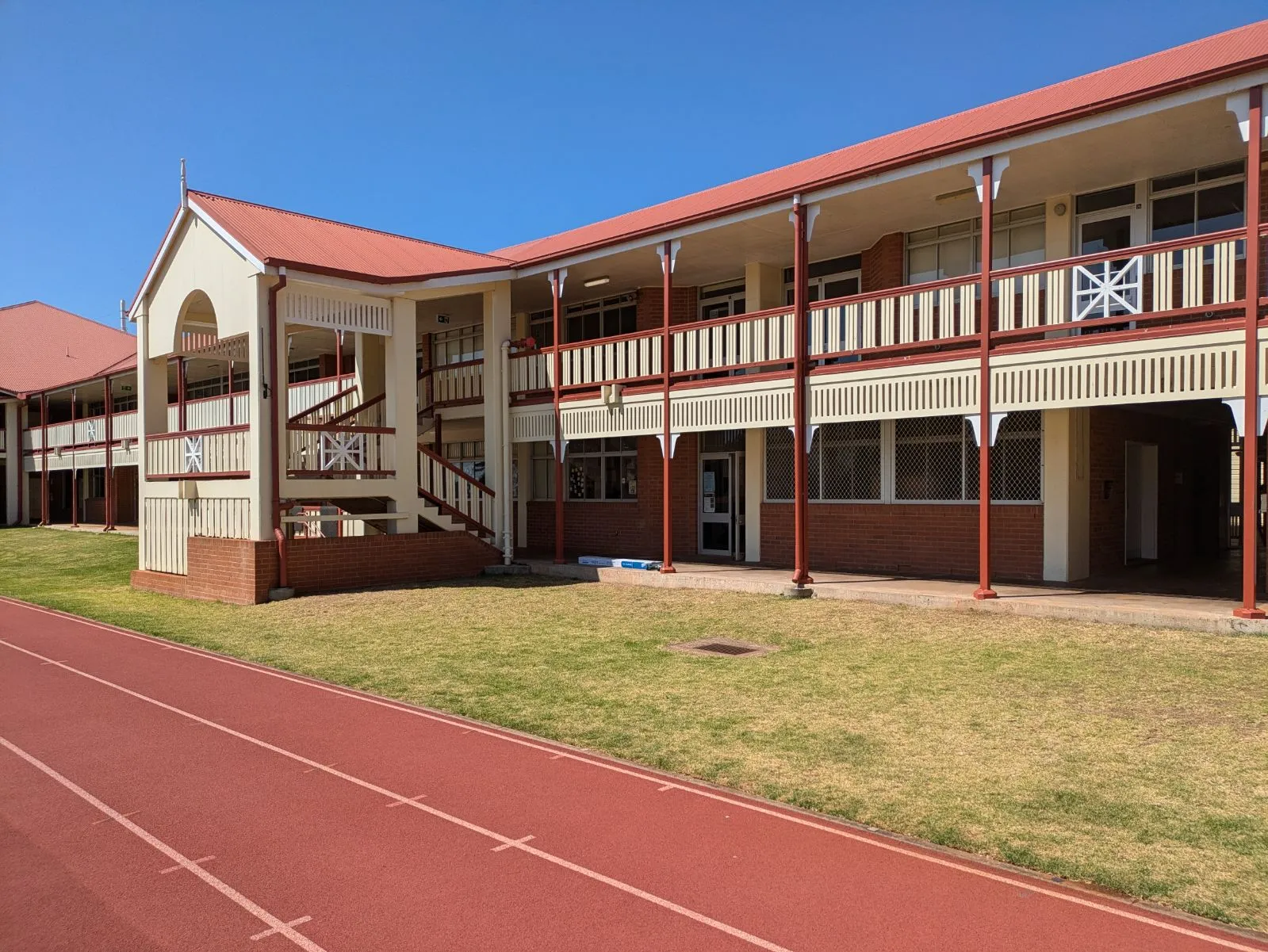 Two-storey Glennie School verandah classroom block beside a running track