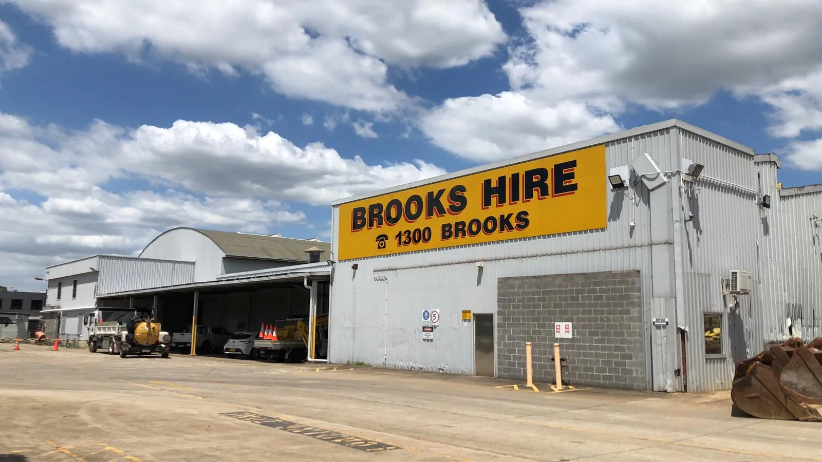 Large Brooks Hire equipment-hire shed with trucks and machinery on the yard