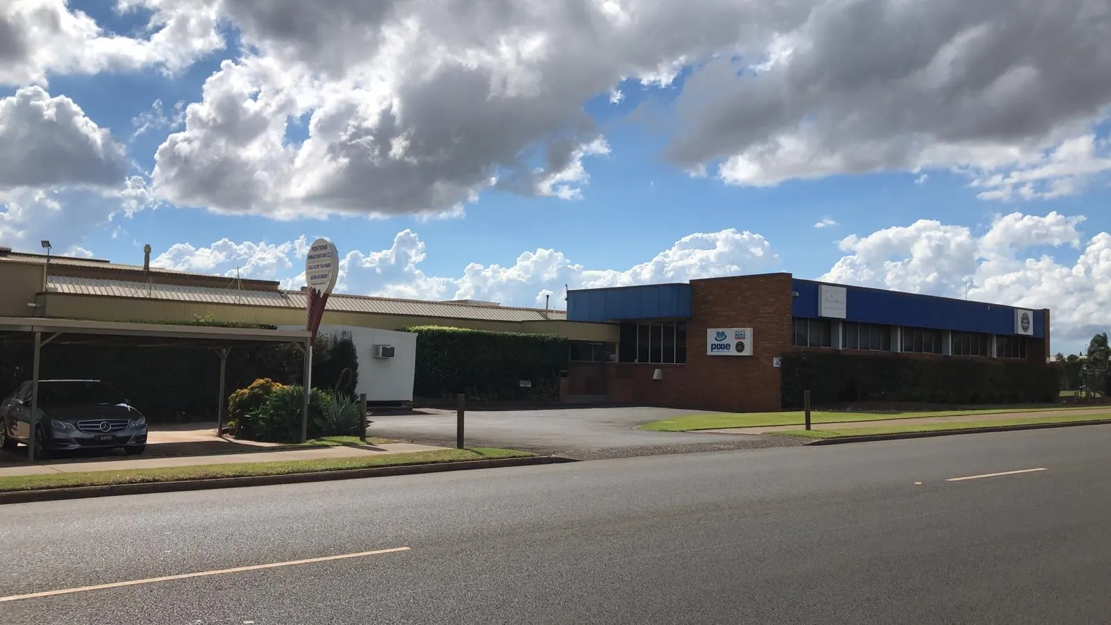 Long brick-and-steel industrial manufacturing facility seen from the road