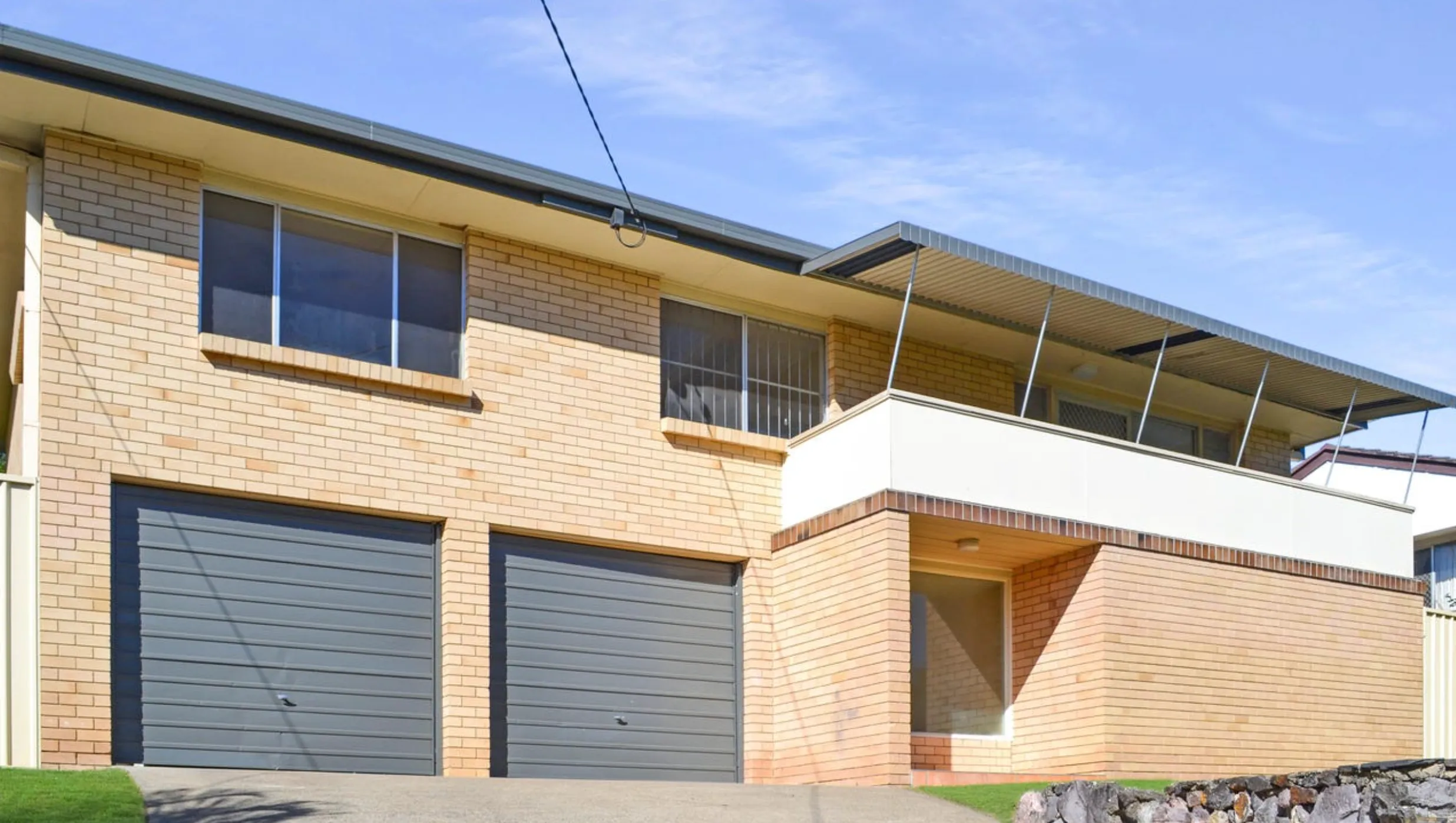 Modern double-storey brick home with double garage and rendered balcony