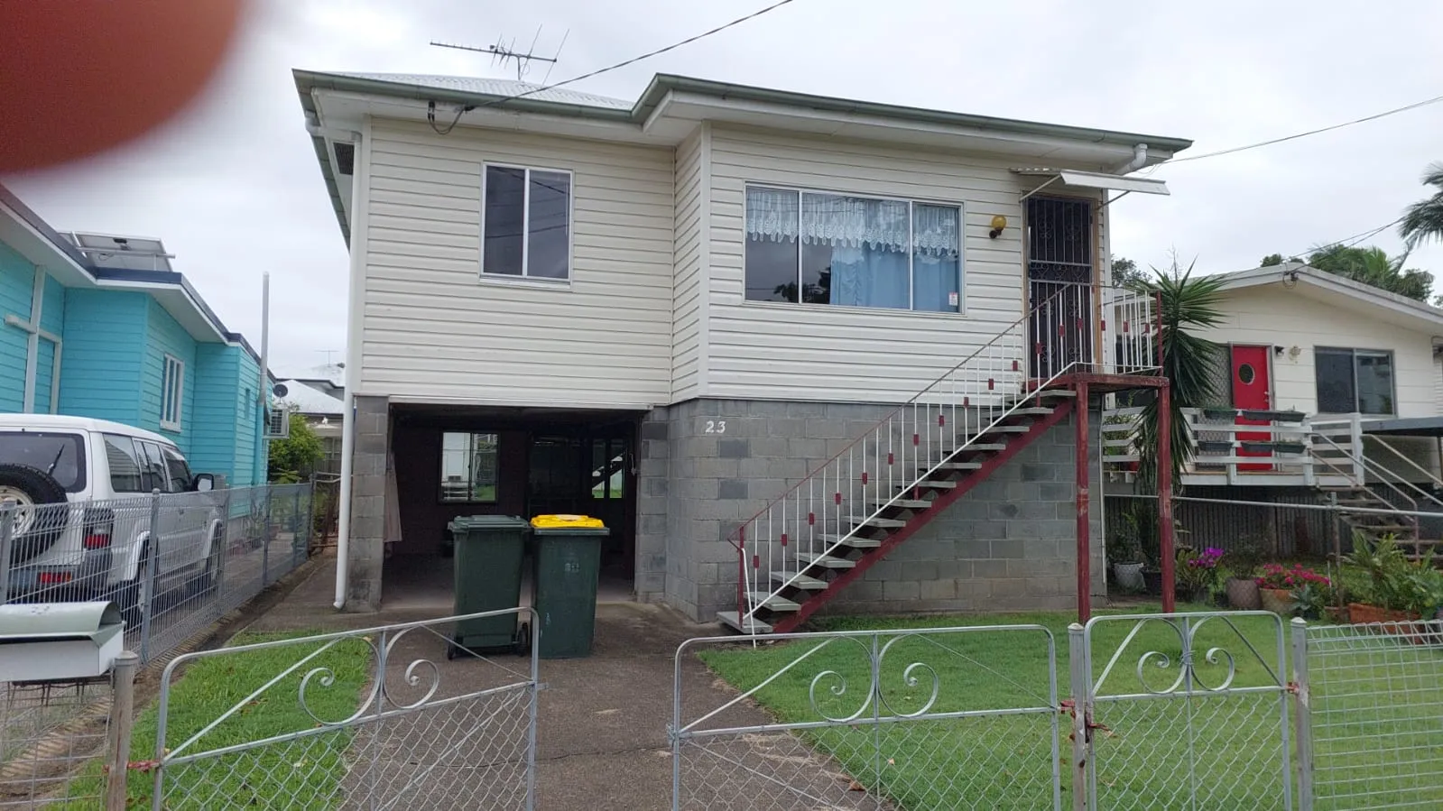 High-set weatherboard Queenslander on a suburban street