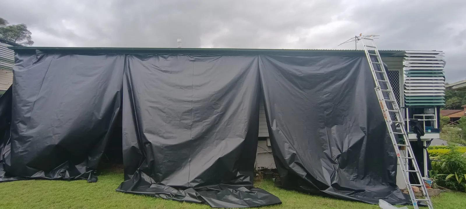 House wrapped in poly sheeting enclosure ready for controlled removal