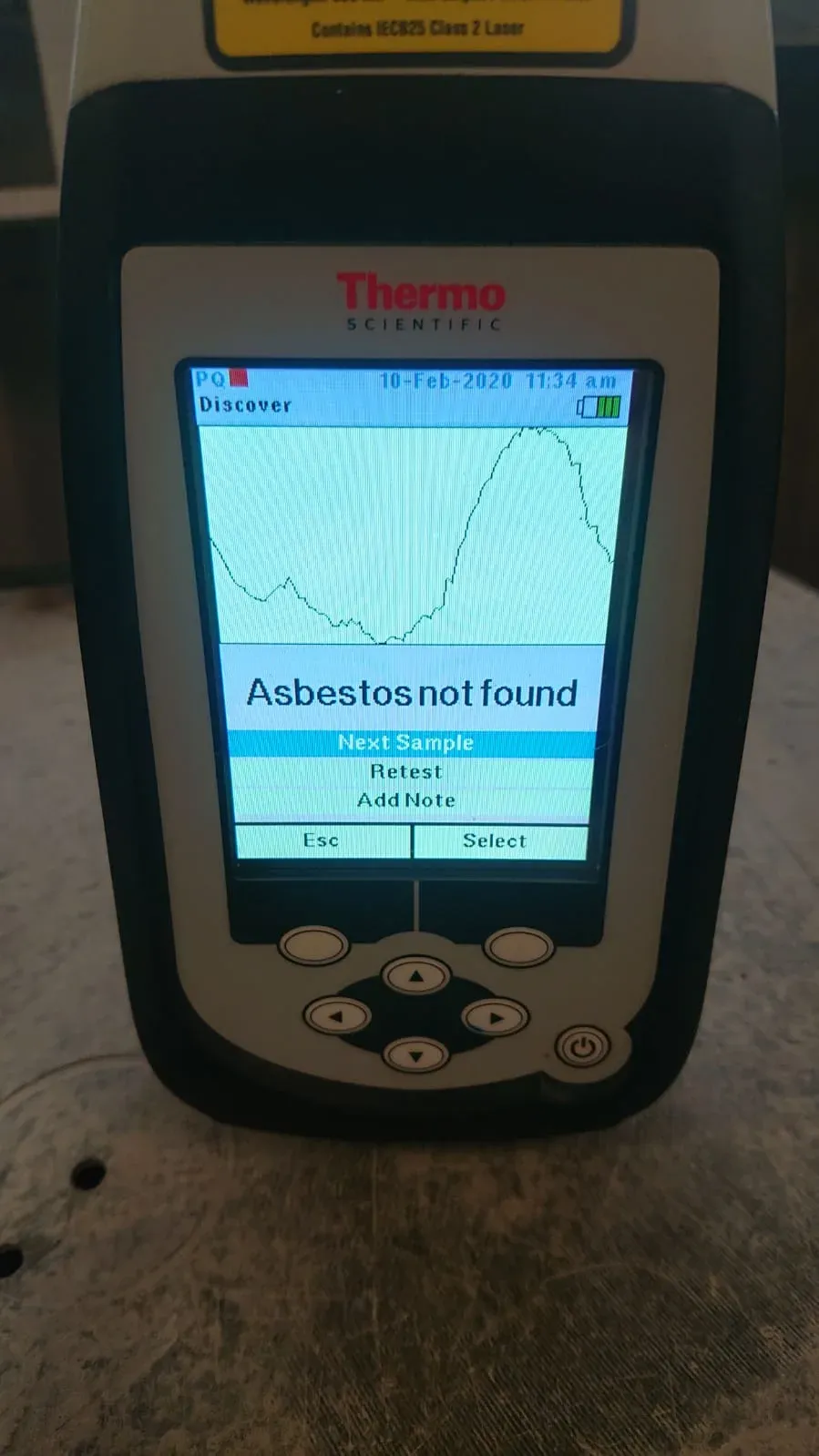 Handheld asbestos analyser showing a result on-site